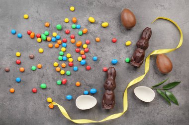 Çikolata Paskalya tavşanları ve gri arka plan üzerinde şekerler kompozisyonu