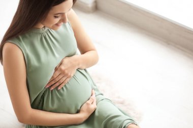 Kapalı katta oturan genç hamile kadın