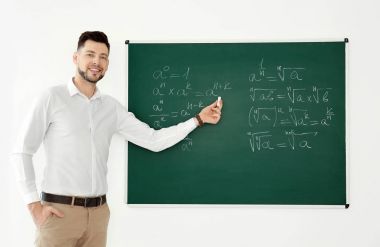 Erkek öğretmen sınıfta blackboard yakınındaki malzeme açıklayan