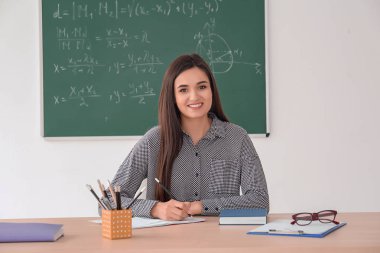 Genç kadın öğretmen sınıfta masada çalışma