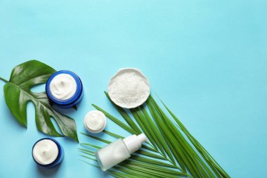 Farklı cilt bakımı kozmetik ürünleri renk arka plan, üstten görünüm üzerinde yeşil yaprakları ile