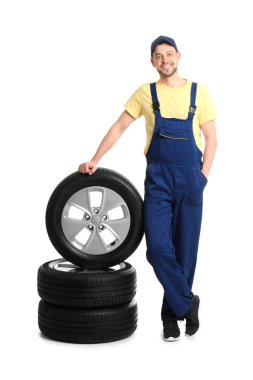 Beyaz arka plan üzerinde araba lastikleri ile erkek makinist