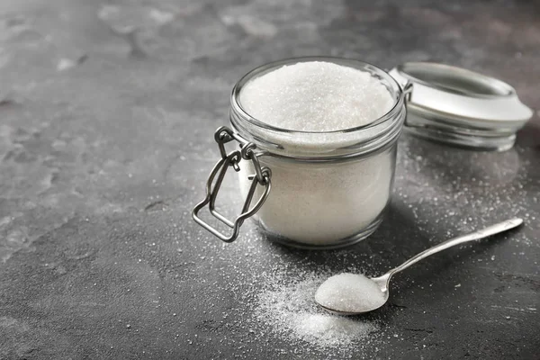 Vaso di vetro con zucchero puro su fondo grigio — Foto Stock