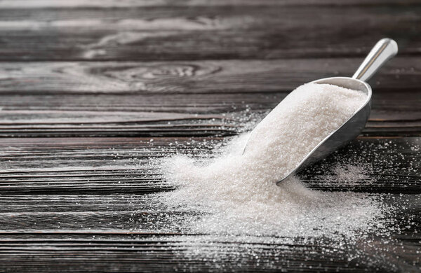 Металлическая сенсация с чистым сахаром на деревянном фоне
