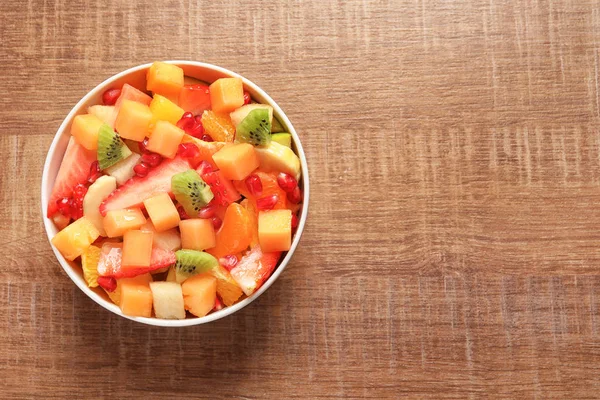 Cuenco con frutas frescas cortadas en mesa de madera, vista superior — Foto de Stock