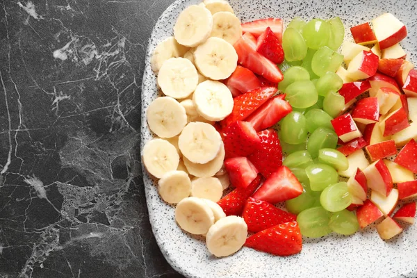 Plate with fresh cut fruits on table, top view