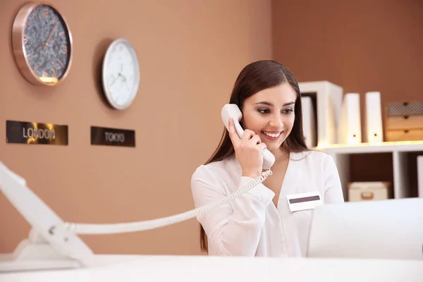 Recepcionista feminina conversando por telefone no balcão de check-in do hotel — Fotografia de Stock