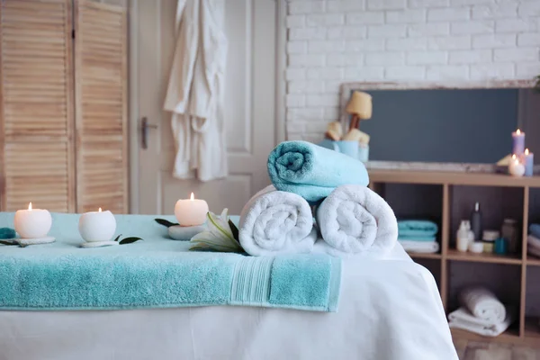 Mesa de masaje con toallas, velas y piedras en el salón de spa —  Fotos de Stock