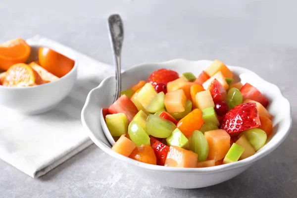 Bol avec salade de fruits frais sur fond gris — Photo