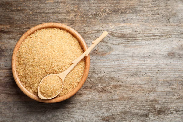 Kase ve kahverengi şeker ahşap zemin üzerine kaşıkla