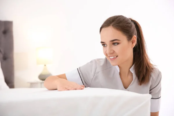 Mladá služka tvorby posteli v hotelovém pokoji — Stock fotografie
