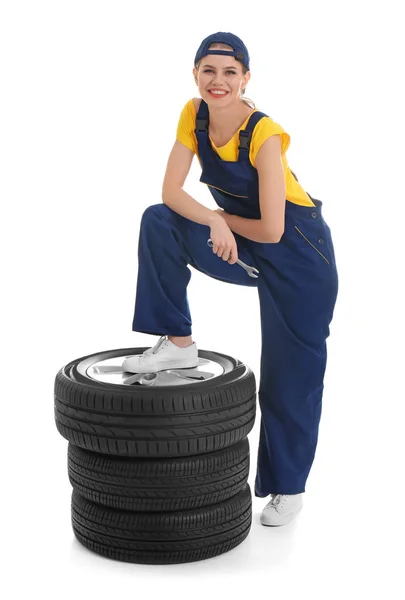 Mecânico feminino com pneus de carro no fundo branco — Fotografia de Stock