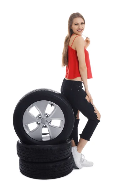 Jovem mulher em roupa sedutora com pneus de carro no fundo branco — Fotografia de Stock