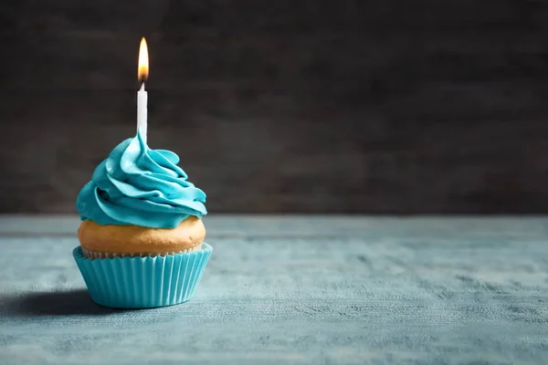 Delicioso cupcake de cumpleaños con vela encendida en la mesa —  Fotos de Stock