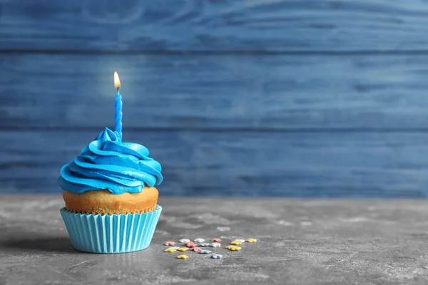 Delicioso cupcake de cumpleaños con vela encendida en la mesa —  Fotos de Stock