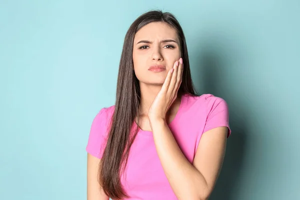 Junge Frau mit empfindlichen Zähnen auf farbigem Hintergrund — Stockfoto