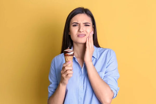 Jovem com dentes sensíveis e sorvete frio no fundo de cor — Fotografia de Stock