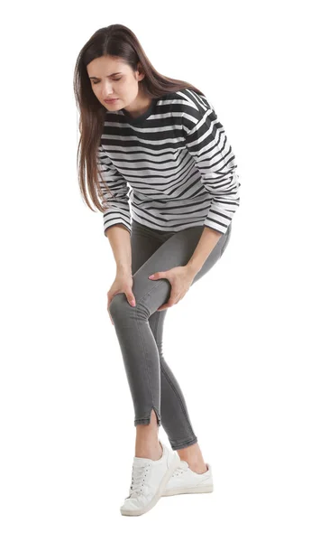 Mladá žena trpí bolestí kolena na bílém pozadí — Stock fotografie