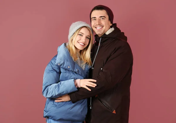 Pareja joven en ropa de abrigo sobre fondo de color. Listo para vacaciones de invierno — Foto de Stock