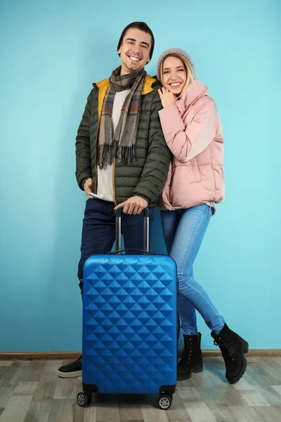 Jeune couple avec valise près du mur de couleur. Prêt pour les vacances d'hiver — Photo