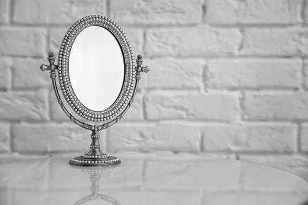 Elegante espejo en la mesa cerca de la pared de ladrillo —  Fotos de Stock