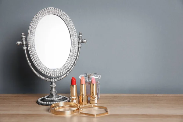 Elegante espejo, productos cosméticos y accesorios en la mesa — Foto de Stock