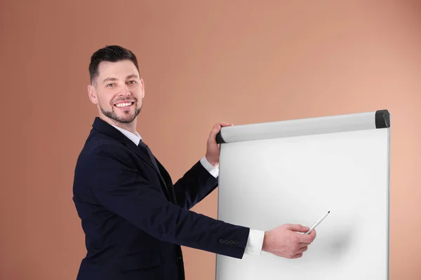 Jonge business trainer in de buurt van flip-over op kleur achtergrond — Stockfoto