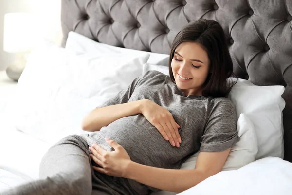 Mujer embarazada joven acostada en la cama en casa — Foto de Stock