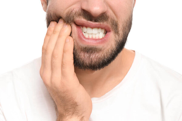 Young man suffering from toothache on white background