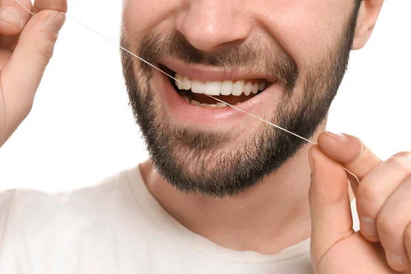 Ung man tandtråd tänderna på vit bakgrund — Stockfoto