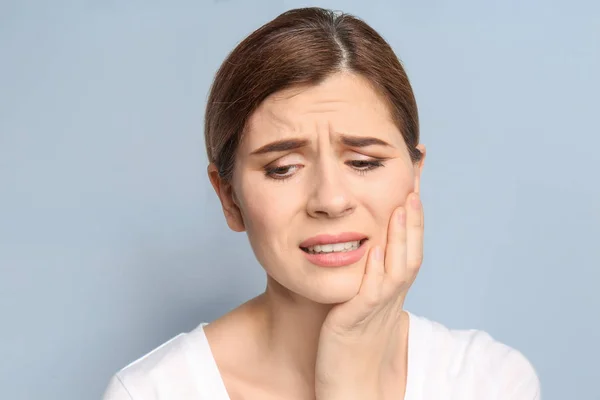 Junge Frau mit Zahnschmerzen auf grauem Hintergrund — Stockfoto