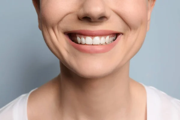 Mujer joven con hermosa sonrisa sobre fondo gris. Blanqueamiento dental — Foto de Stock