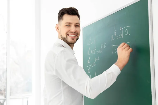 Professor do sexo masculino escrevendo em quadro negro em sala de aula — Fotografia de Stock