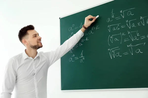 Homme enseignant écriture sur tableau noir dans la salle de classe — Photo