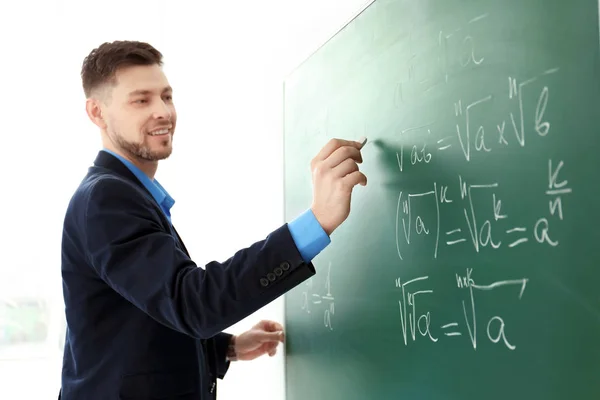 Homme enseignant écriture sur tableau noir dans la salle de classe — Photo