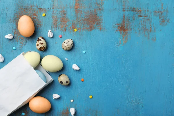 Ahşap arka plan üzerinde üstten görünüm kağıt paketi ile Paskalya yumurta — Stok fotoğraf