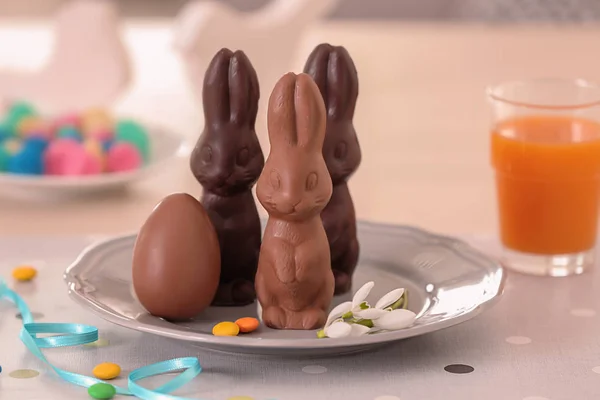 Placa con conejitos de Pascua de chocolate y huevo en la mesa —  Fotos de Stock