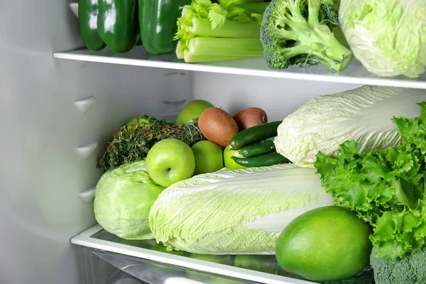 Legumes verdes diferentes e frutas em prateleiras do refrigerador — Fotografia de Stock