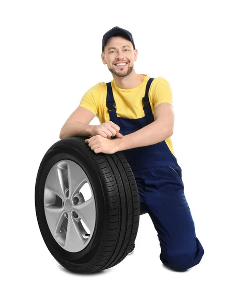Mecânico masculino com pneu de carro no fundo branco — Fotografia de Stock