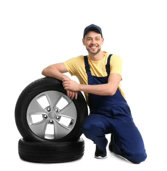 Mecânico masculino com pneus de carro no fundo branco — Fotografia de Stock