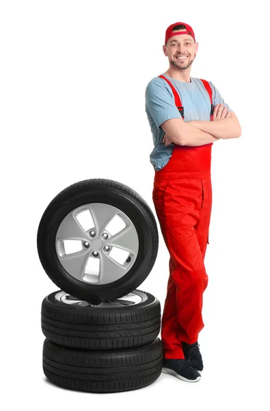 Мужчина-механик с автомобильными шинами на белом фоне — стоковое фото