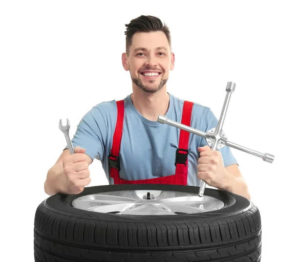 Mecânico masculino com pneu de carro e ferramentas no fundo branco — Fotografia de Stock