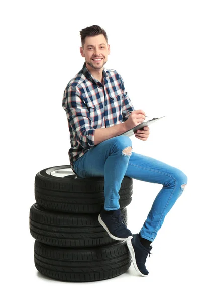 Jovem com pneus de carro no fundo branco — Fotografia de Stock