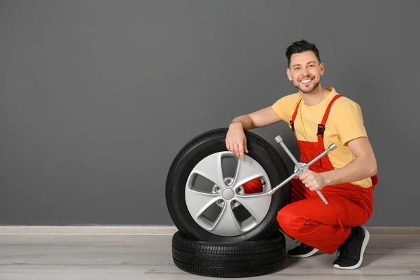 Mužské mechanik s auto pneumatiky na barvu zdi pozadí — Stock fotografie