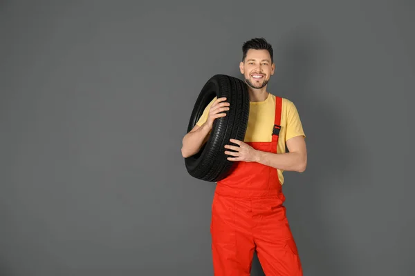 Mužské mechanik s auto pneumatiky na barvu pozadí — Stock fotografie