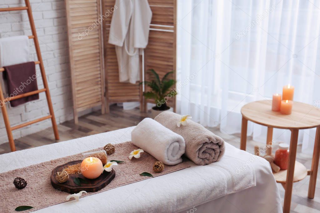 Massage table with towels, candle and sea salt in spa salon