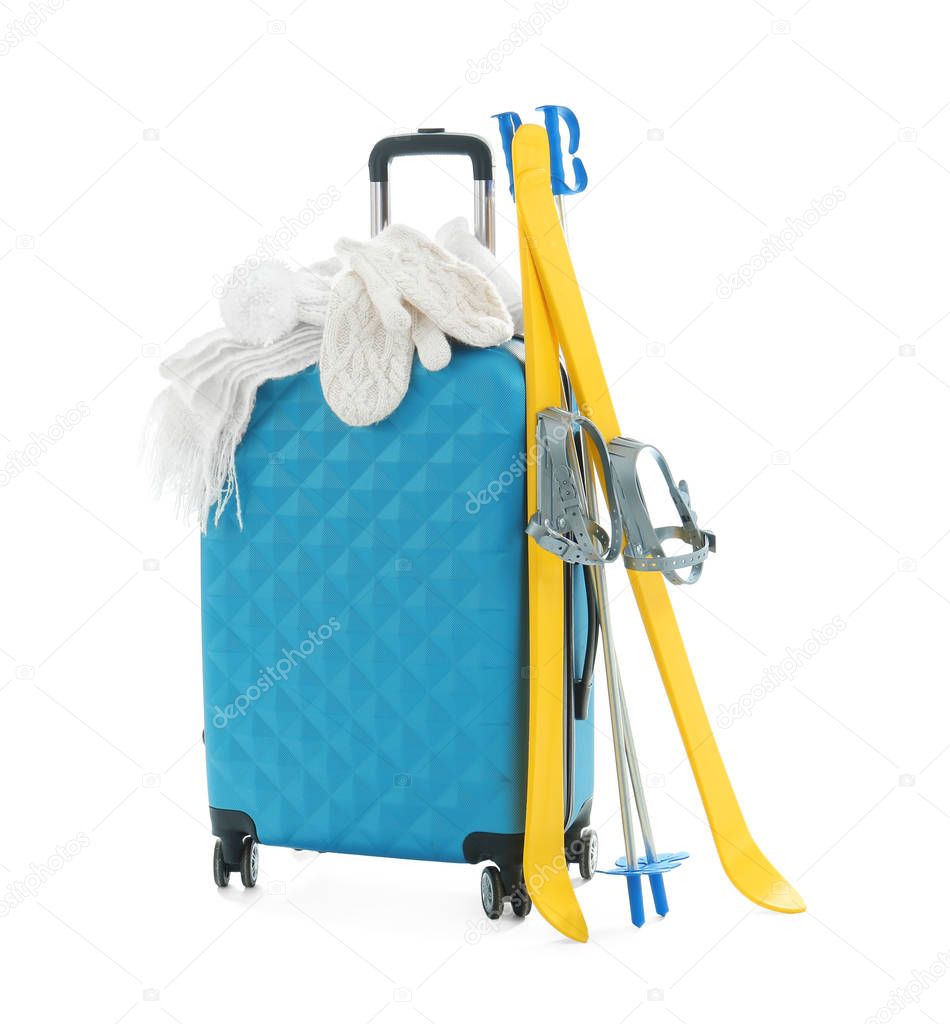 Suitcase with warm clothes and ski equipment on white background. Winter vacation concept