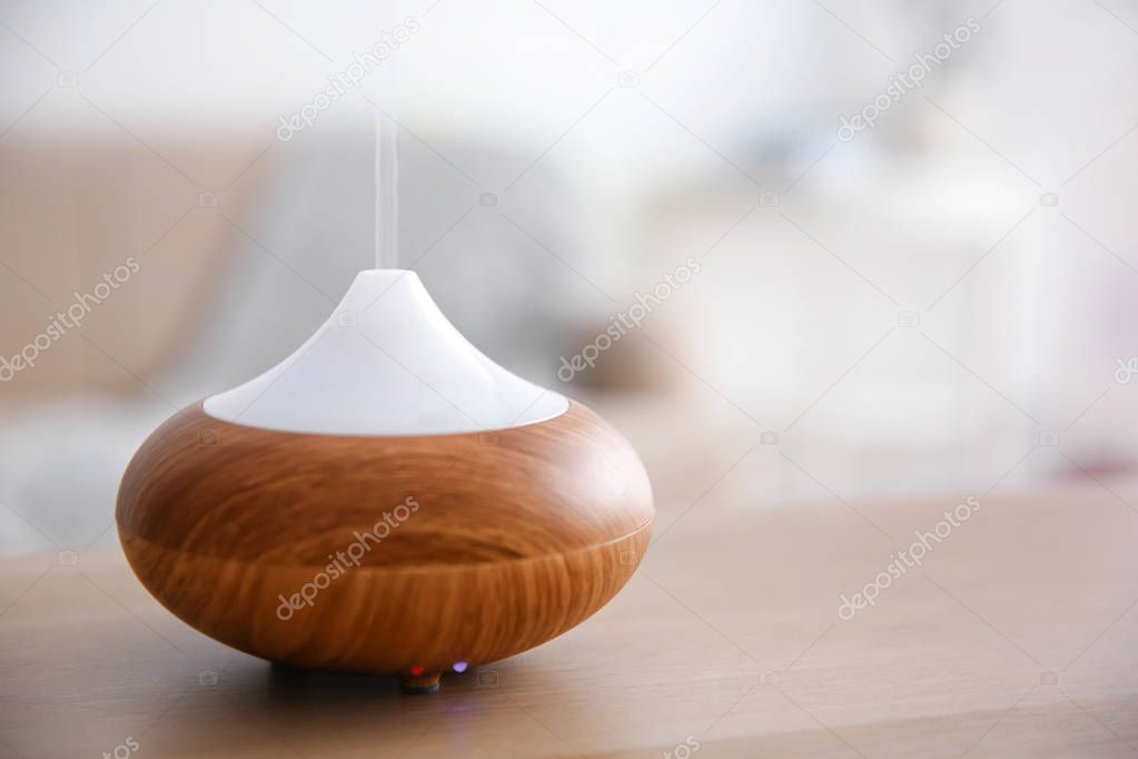 Aroma oil diffuser on table against blurred background
