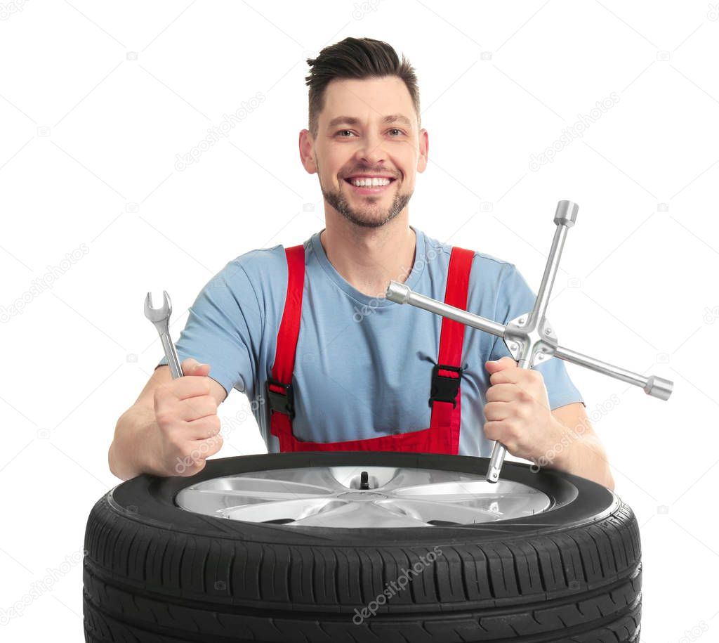 Male mechanic with car tire and tools on white background