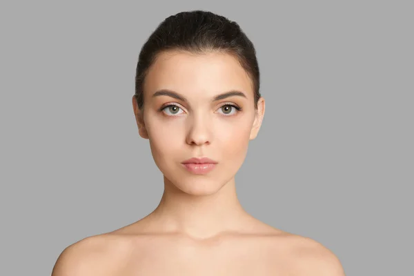 Mujer joven con hermoso maquillaje sobre fondo gris. Productos cosméticos profesionales —  Fotos de Stock